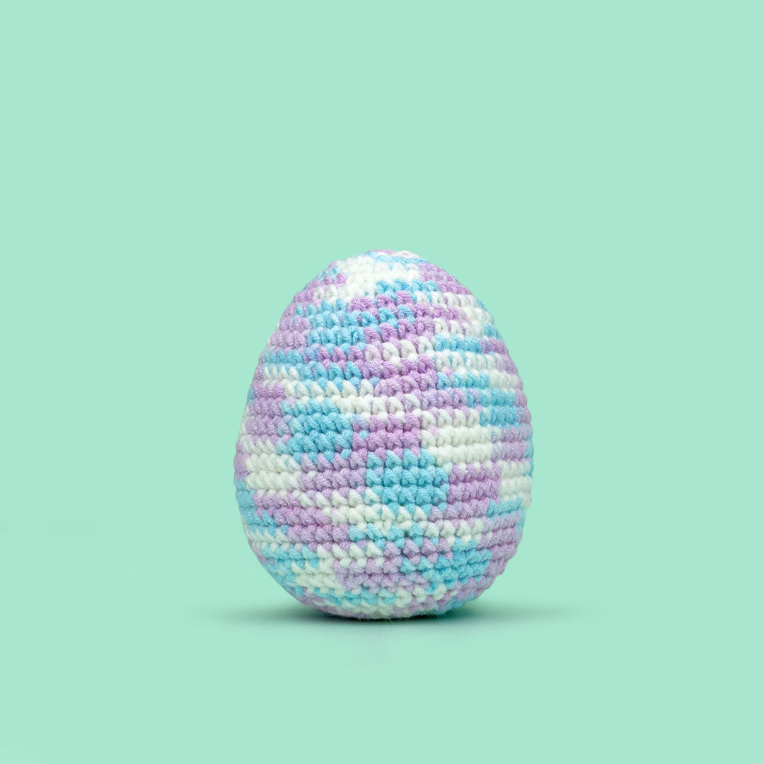The Cute Crochet handmade Easter egg - white base with pastel pink, blue, and purple yarn accents